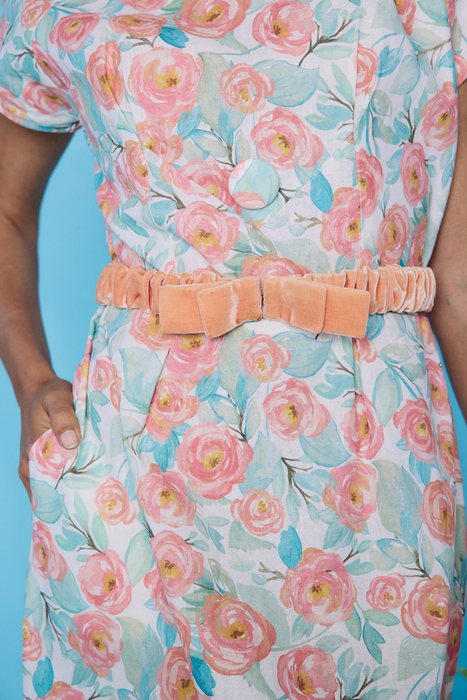 Floral dress with a peach belt against a blue background