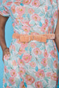 Floral dress with a peach belt against a blue background